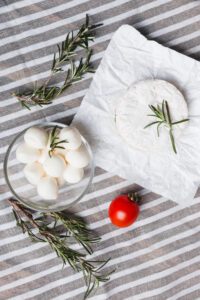 Close-up of fresh Italian cheeses including mozzarella, stracciatella, and scamorza on a kitchen counter.